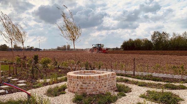Tuin met bakstenen put en veld op achtergrond